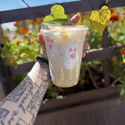 A spring drink with cream in a paw-print cup, held on the patio