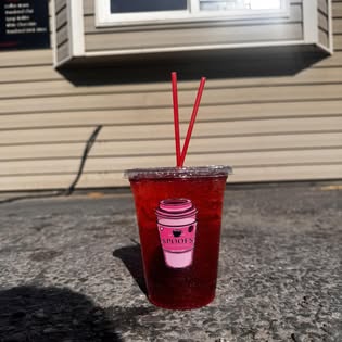A berry-red refresher on the pavement in the daylight outside the window